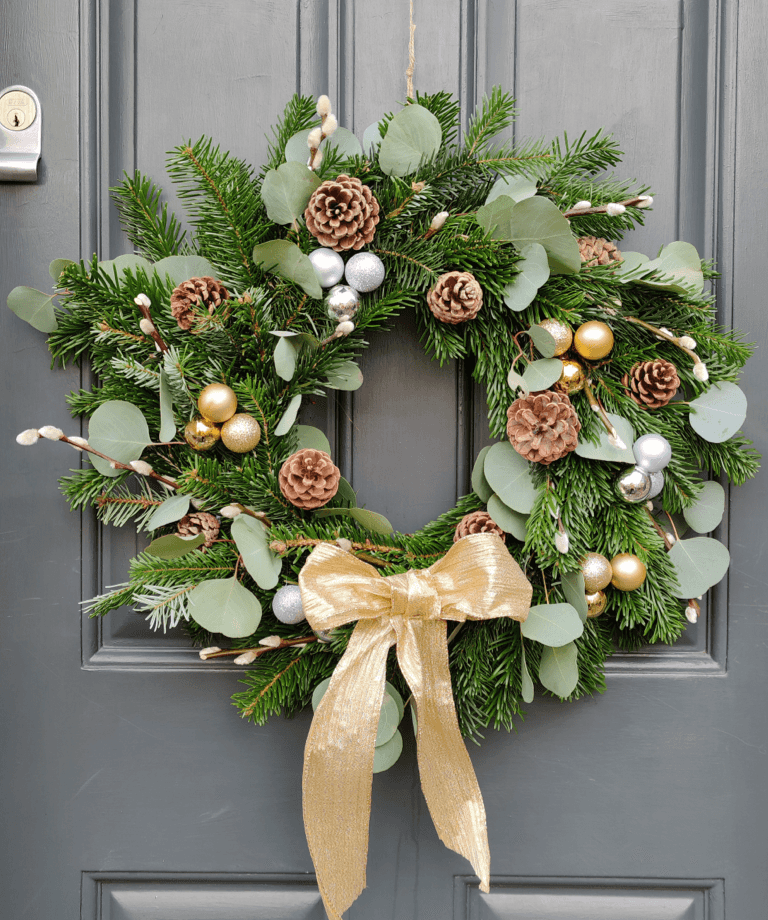 This eye catching wreath will be sure to grab the e attention of all those passing by. Adorned with gold and silver baubles, pine cones, pussy willow and eucalyptus and finished with a shimmering gold bow.